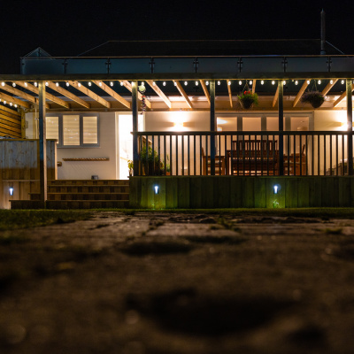 Rear garden with lawn, decking and atmospheric lighting